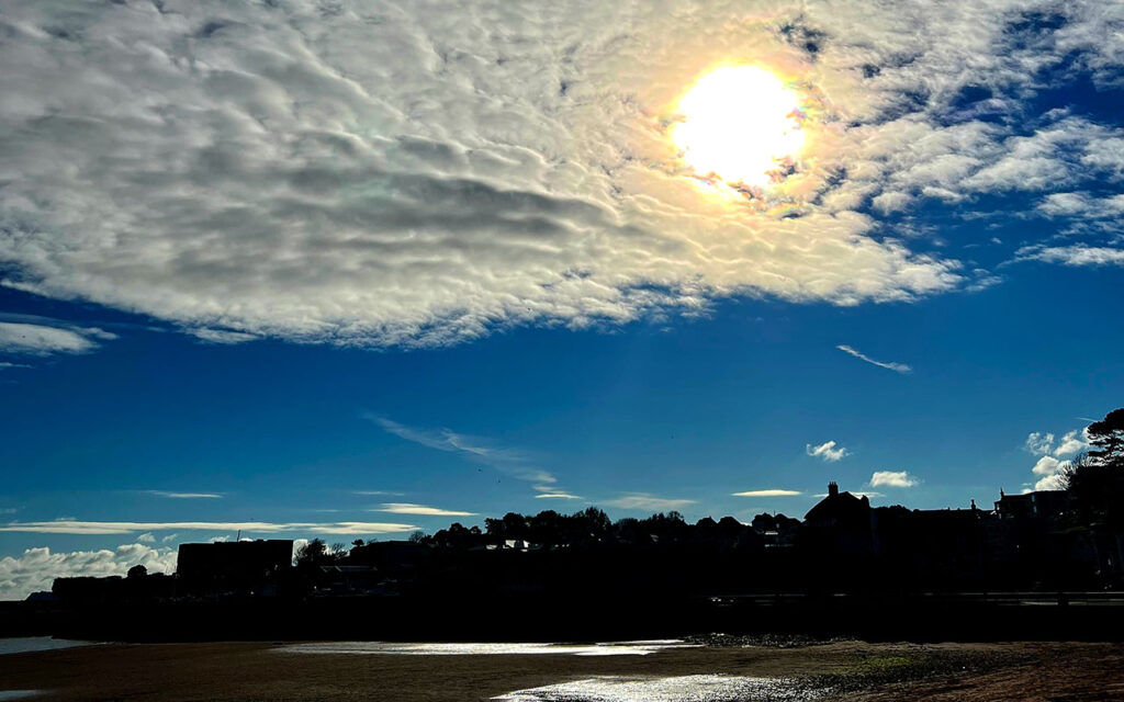 autumn sun in the sky behind some clouds